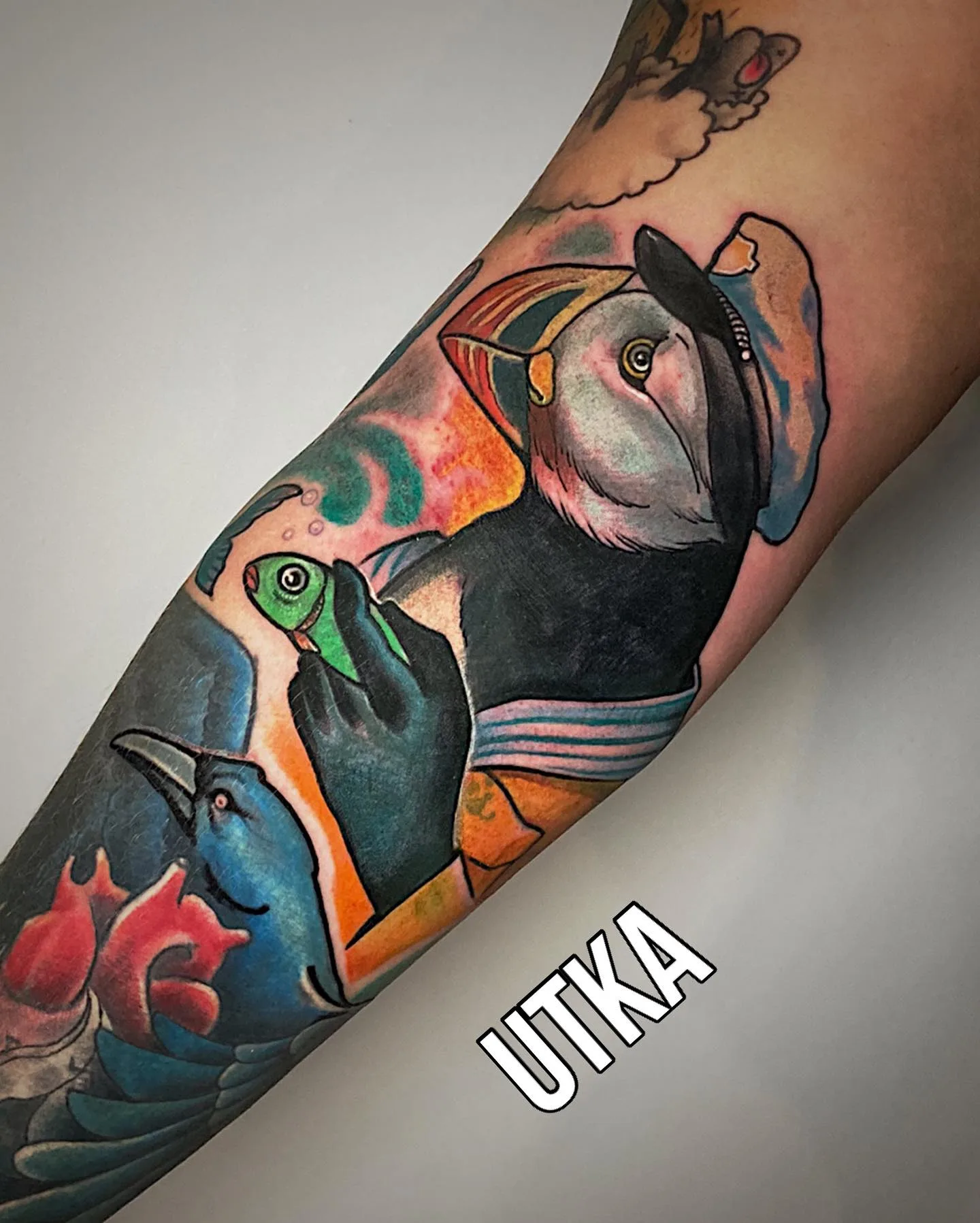 Kolorowy tatuaż maskotki-ptaka na przedramieniu